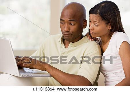 Picture - Couple in living room using laptop. Fotosearch