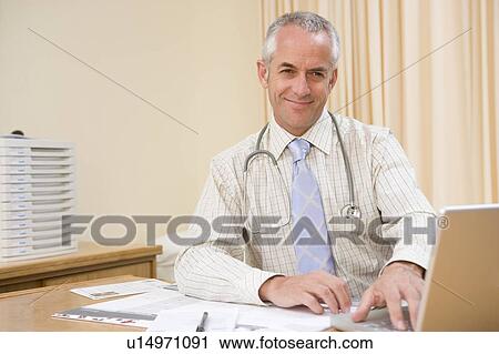 Doctor using laptop in doctor's office smiling View Large Photo Image Stock Image - Doctor using laptop in doctor's office smiling. Fotosearch