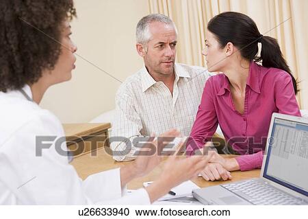 Doctor with laptop and couple in doctor's office frowning View Large Photo Image Stock Image - Doctor with laptop and couple in doctor's office frowning. Fotosearch