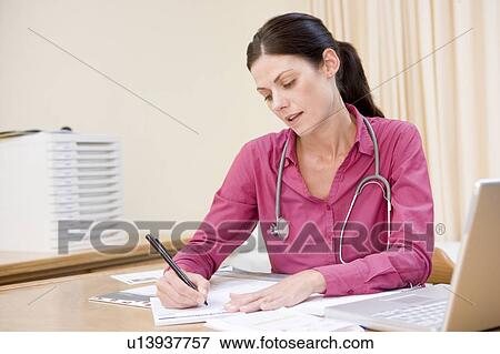 Stock Photo - Doctor with laptop writing in doctor's office. Fotosearch