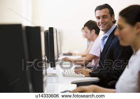Four people in computer room with one man wearing a suit smiling View Large Photo Image Stock Photograph - Four people in computer room with one man wearing a suit smiling. Fotosearch