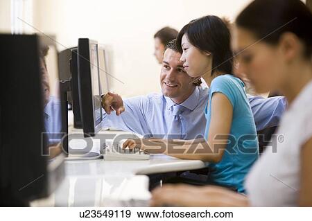 Stock Photo - Man assisting woman in computer room smiling. Fotosearch