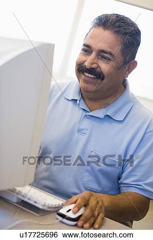 Man at computer smiling and looking at monitor (high key) View Large Photo Image Stock Photograph - Man at computer smiling and looking at monitor (high key). Fotosearch
