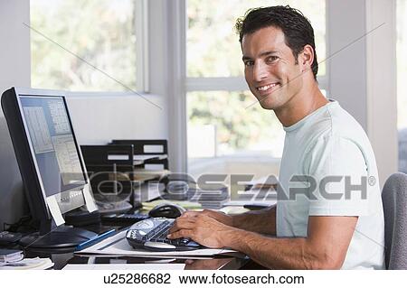 Man in home office using computer and smiling View Large Photo Image Stock Image - Man in home office using computer and smiling. Fotosearch