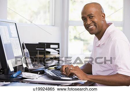 Man in home office using computer and smiling View Large Photo Image Stock Photography - Man in home office using computer and smiling. Fotosearch