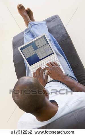 Stock Image - Man sitting in chair using laptop. Fotosearch