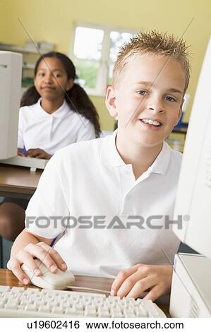 Stock Photograph - Student at computer terminal with student in background (selective focus). Fotosearch
