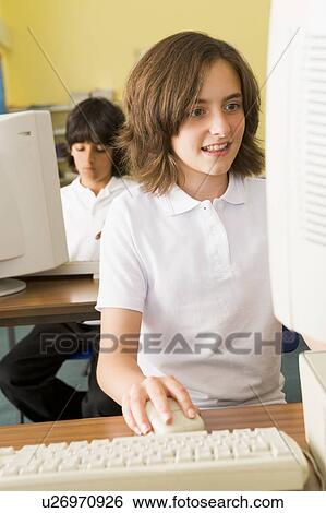 Stock Photograph - Student at computer terminal with student in background (selective focus). Fotosearch