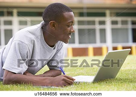 Student lying outdoors on lawn with laptop View Large Photo Image Stock Photograph - Student lying outdoors on lawn with laptop. Fotosearch
