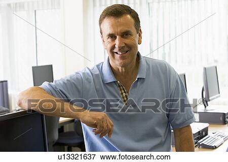 Stock Photo - Teacher by computer terminals smiling (high key). Fotosearch