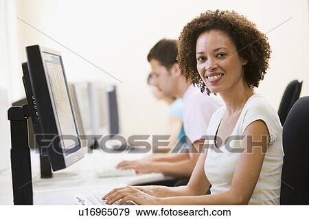 Stock Photo - Three people in computer room typing and smiling. Fotosearch