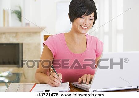 Woman in dining room with laptop smiling View Large Photo Image Stock Photo - Woman in dining room with laptop smiling. Fotosearch