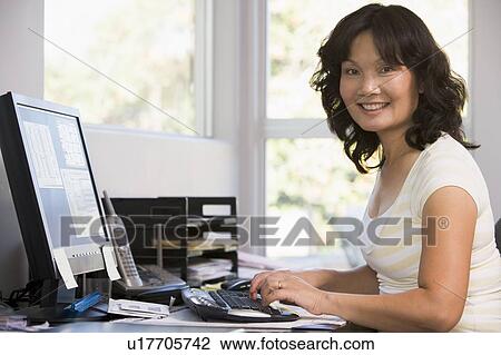 Woman in home office using computer and smiling View Large Photo Image Stock Image - Woman in home office using computer and smiling. Fotosearch