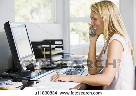 Woman in home office with computer using telephone smiling View Large Photo Image Picture - Woman in home office with computer using telephone smiling. Fotosearch