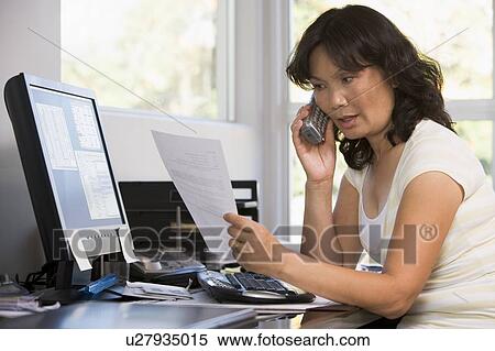 Woman in home office with paperwork using telephone View Large Photo Image Stock Photography - Woman in home office with paperwork using telephone. Fotosearch