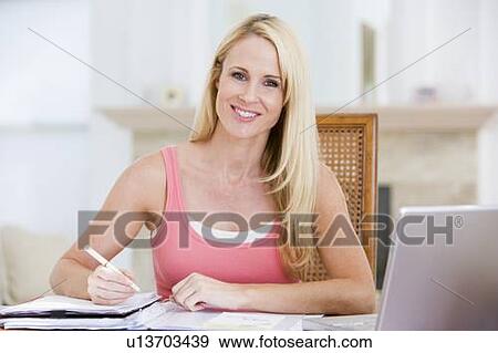 Stock Photo - Woman in kitchen with newspaper and coffee smiling. Fotosearch