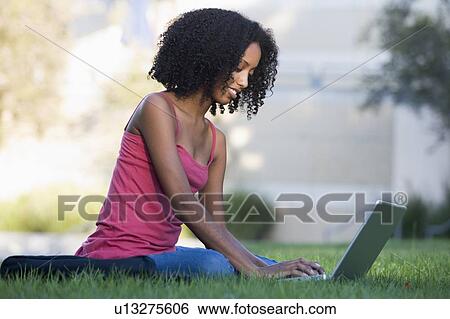 Woman outdoors sitting on grass with laptop (selective focus) View Large Photo Image Stock Photograph - Woman outdoors sitting on grass with laptop (selective focus). Fotosearch