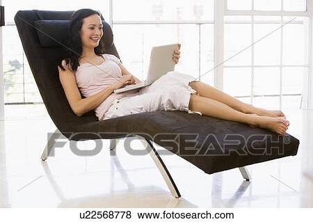 Woman sitting in chair using laptop smiling View Large Photo Image Stock Photo - Woman sitting in chair using laptop smiling. Fotosearch
