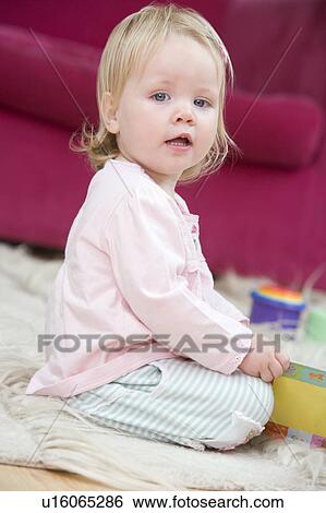 Stock Photograph - Baby in living room with toys and book. Fotosearch
