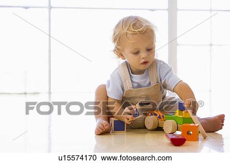 Stock Image - Baby indoors playing with toy truck. Fotosearch