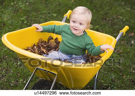Baby outdoors sitting in wheelbarrow smiling (selective focus) View Large Photo Image Stock Photograph - Baby outdoors sitting in wheelbarrow smiling (selective focus). Fotosearch