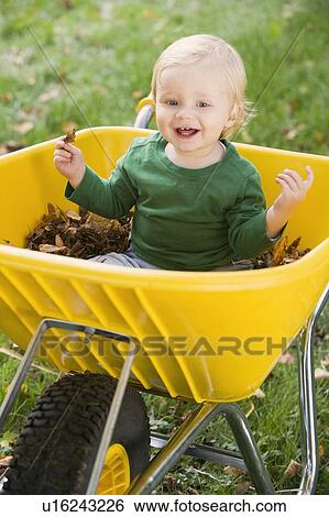 Baby outdoors sitting in wheelbarrow smiling (selective focus) View Large Photo Image Stock Photograph - Baby outdoors sitting in wheelbarrow smiling (selective focus). Fotosearch