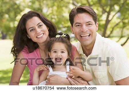 Picture - Family sitting outdoors smiling. Fotosearch
