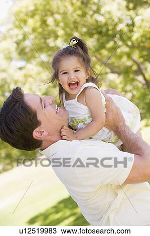 Father holding daughter outdoors smiling View Large Photo Image Stock Image - Father holding daughter outdoors smiling. Fotosearch
