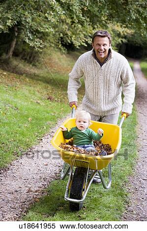 Father pushing baby son in wheelbarrow View Large Photo Image Stock Photography - Father pushing baby son in wheelbarrow. Fotosearch