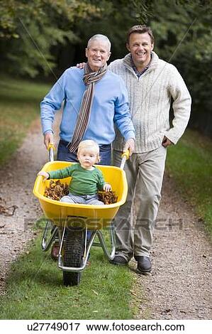 Grandfather and Father outdoors pushing grandson in wheelbarrow and smiling (selective focus) View Large Photo Image Stock Photo - Grandfather and Father outdoors pushing grandson in wheelbarrow and smiling (selective focus) . Fotosearch