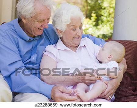 Stock Photo - Grandparents outdoors on patio with baby smiling. Fotosearch