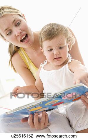 Stock Image - Mother and baby reading book indoors and pointing. Fotosearch