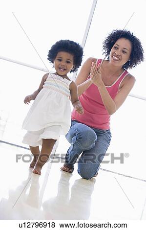 Stock Photo - Mother and daughter indoors playing and smiling. Fotosearch