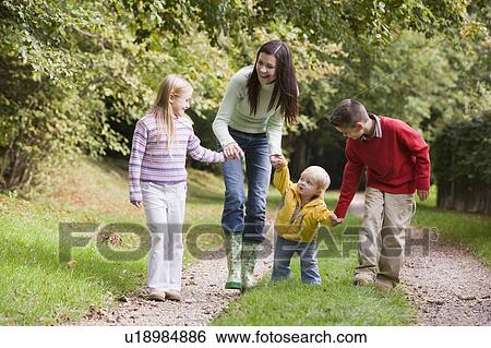 Mother and three young children walking on path outdoors smiling View Large Photo Image Stock Photograph - Mother and three young children walking on path outdoors smiling. Fotosearch