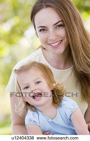Stock Photo - Mother holding daughter outdoors smiling. Fotosearch