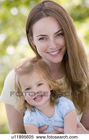 Stock Photography - Mother holding daughter outdoors smiling. Fotosearch