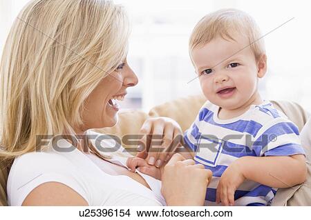 Mother in living room holding baby smiling View Large Photo Image Picture - Mother in living room holding baby smiling. Fotosearch