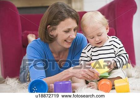 Mother in living room playing with baby smiling View Large Photo Image Stock Photo - Mother in living room playing with baby smiling. Fotosearch
