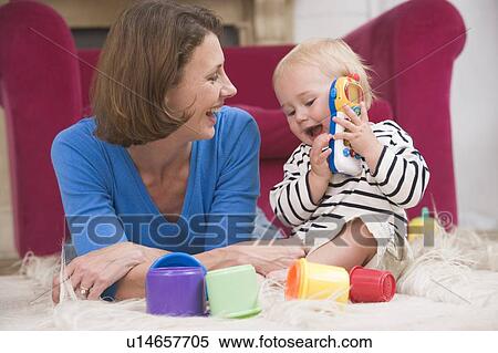 Mother in living room playing with baby smiling View Large Photo Image Stock Photography - Mother in living room playing with baby smiling. Fotosearch