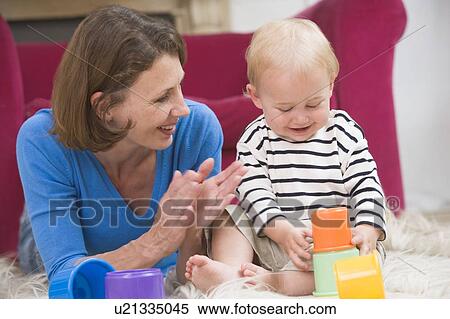 Stock Photography - Mother in living room playing with baby smiling. Fotosearch