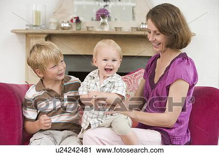 Stock Image - Mother in living room with baby and young boy smiling. Fotosearch