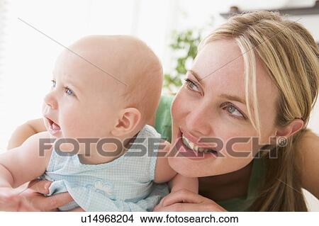 Mother in living room with baby smiling View Large Photo Image Picture - Mother in living room with baby smiling. Fotosearch