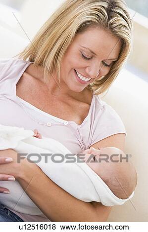 Stock Photo - Mother in living room with baby smiling. Fotosearch