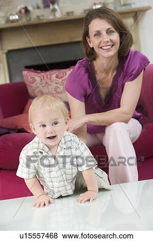 Stock Photo - Mother in living room with baby smiling. Fotosearch