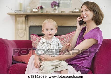 Mother using telephone in living room with baby smiling View Large Photo Image Stock Photo - Mother using telephone in living room with baby smiling. Fotosearch