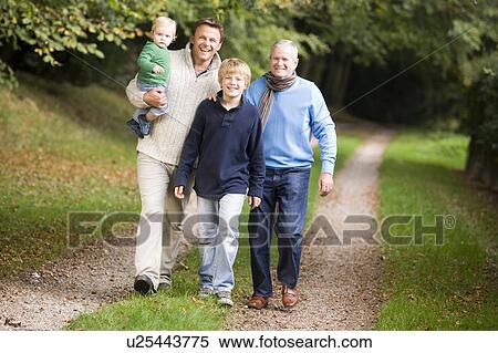 Stock Photography - Two men and two young children walking on path outdoors smiling (selective focus). Fotosearch