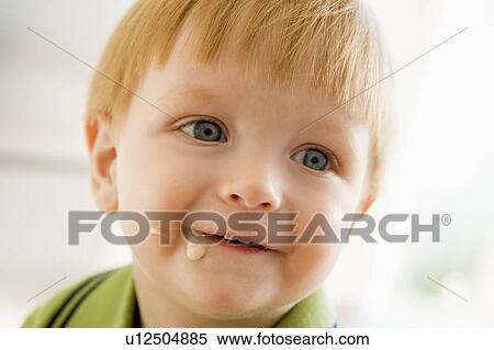 Stock Photography - Young boy eating baby food with mess on face. Fotosearch