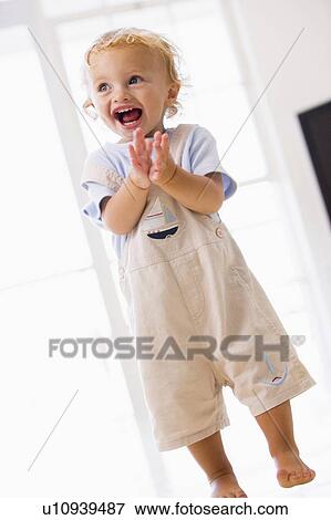Young boy standing indoors applauding and smiling View Large Photo Image Stock Photo - Young boy standing indoors applauding and smiling. Fotosearch