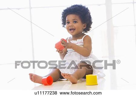 Baby indoors playing with cup toys View Large Photo Image Stock Photo - Baby indoors playing with cup toys. Fotosearch