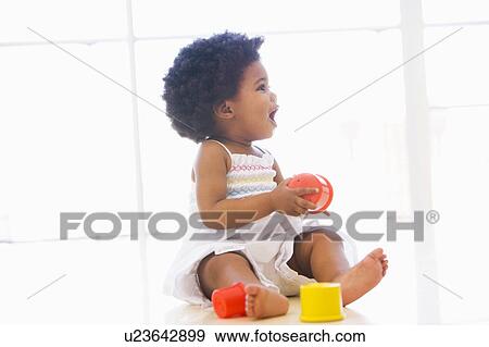 Baby indoors playing with cup toys View Large Photo Image Stock Photo - Baby indoors playing with cup toys. Fotosearch